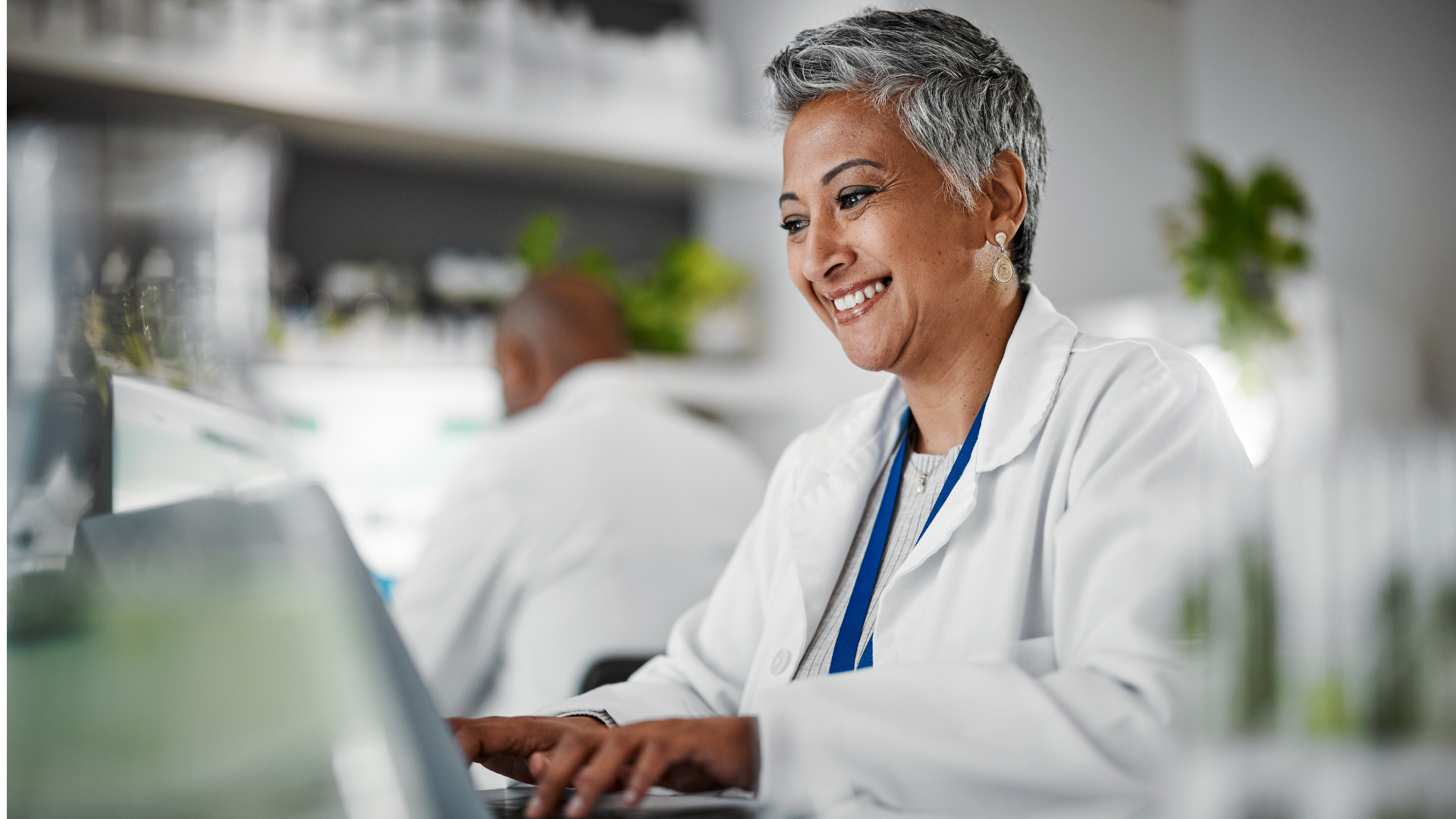Healthcare Provider smiling and entering information into laptop.